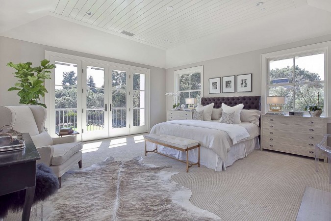 A serene master bedroom with white walls and a cowhide rug.