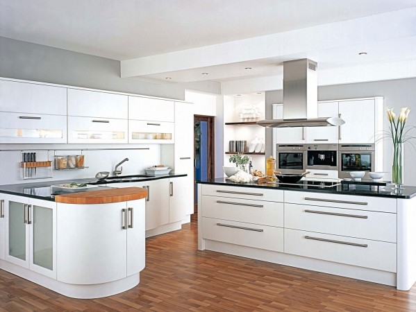 A modern kitchen with white cabinets and wooden floors.