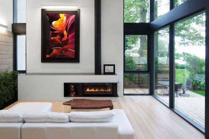 A modern lake home living room with large windows and a fireplace.