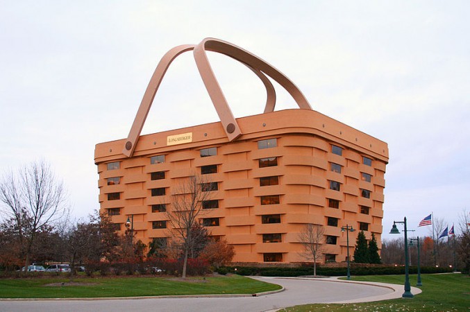 A brown building with a basket on top among houses and buildings.