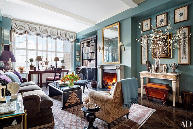 A living room with blue walls and a fireplace designed by Alexa Hampton.