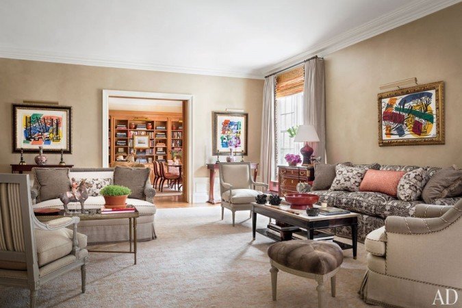 A living room with beige furniture and a bookcase designed by Alexa Hampton.