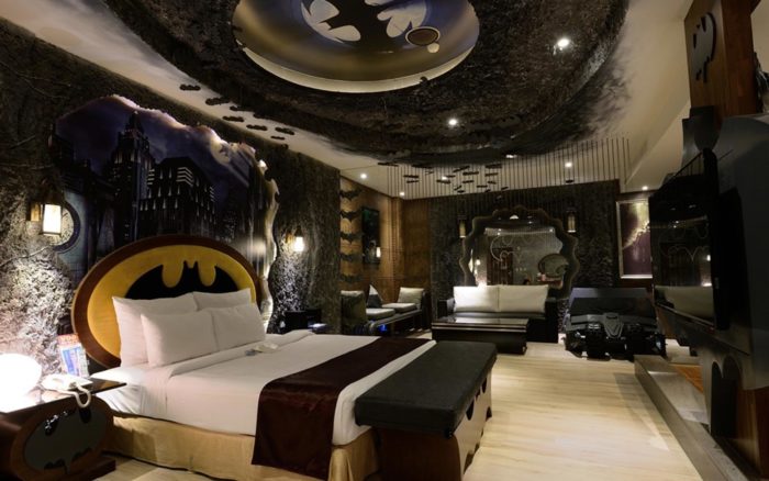 A batman themed bedroom with a bed and a bedside table to inspire your bedroom design.