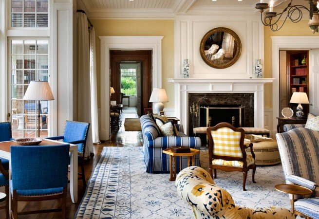 A living room with blue chairs and a fireplace, designed by Alexa Hampton.