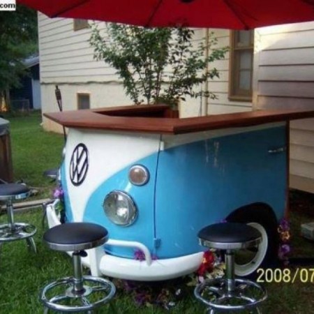 A furniture piece that resembles a VW bus and includes stools.