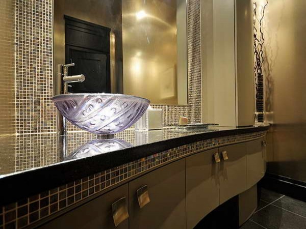 A bathroom with a gold sink and mirror, exuding panache.