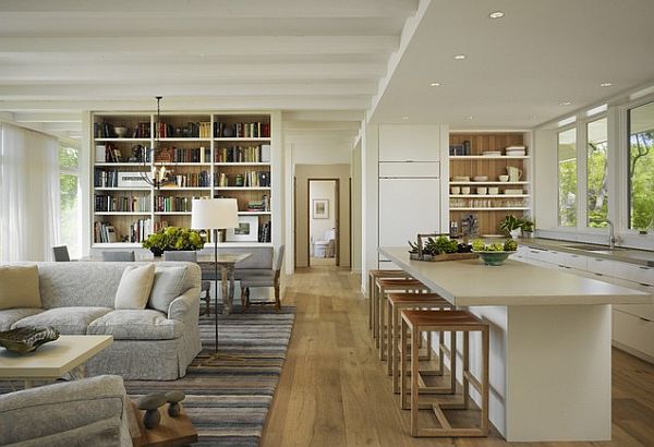 An open floor plan with a white kitchen and living room, featuring bookshelves.