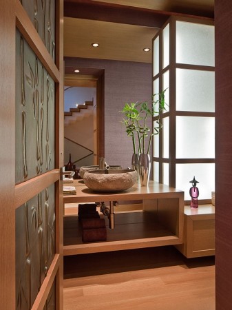 Japanese powder room with wooden doors and a stone sink.