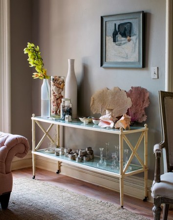 A living room with a pink couch and a glass console table - The Household Champion Bar Cart.