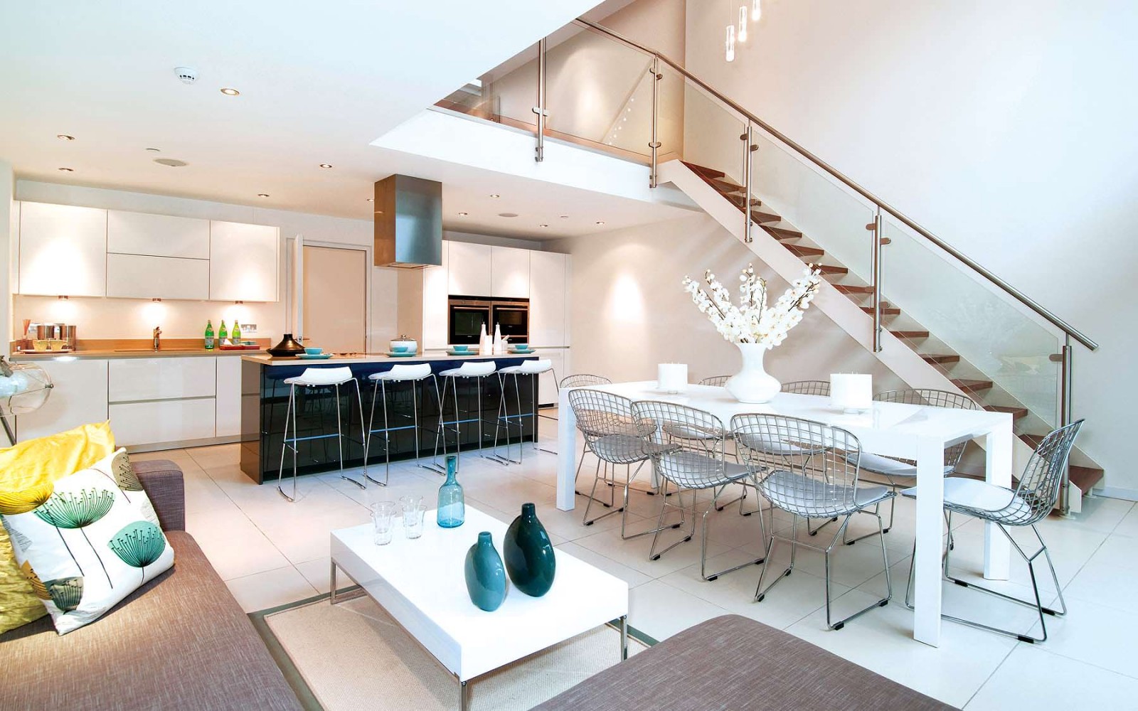 A modern kitchen and dining area with an open floor plan featuring a staircase.