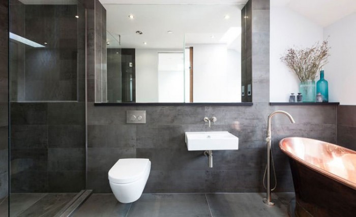 A modern gray bathroom with a copper tub and sink.