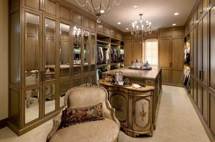Luxury walk-in closet featuring a chandelier and chairs.