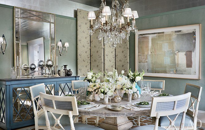 A designer dining room with blue walls and a chandelier featuring Alexa Hampton's focus.
