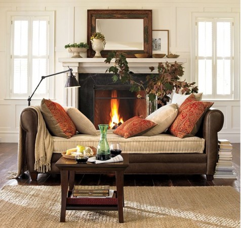 A cozy living room with a fireplace and a couch, featuring autumn-inspired interior design.