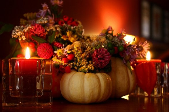 5 Items You Need in Your Home for Fall: A table adorned with candles, pumpkins, and flowers.