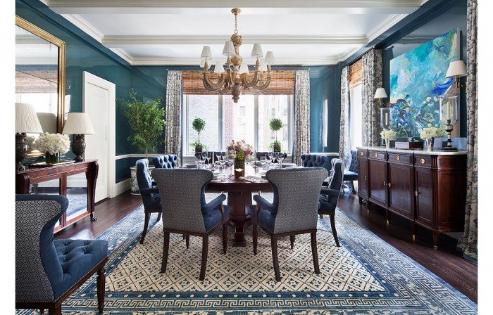 A dining room with blue walls and a chandelier, designed by Alexa Hampton.