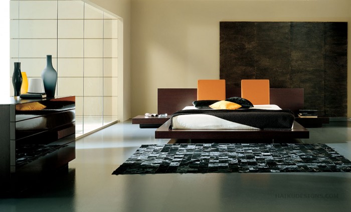 A low-profile bed in a bedroom with black and orange accents.