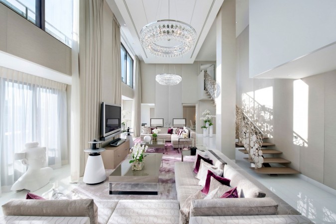 A large living room with low-slung white furniture and a chandelier.