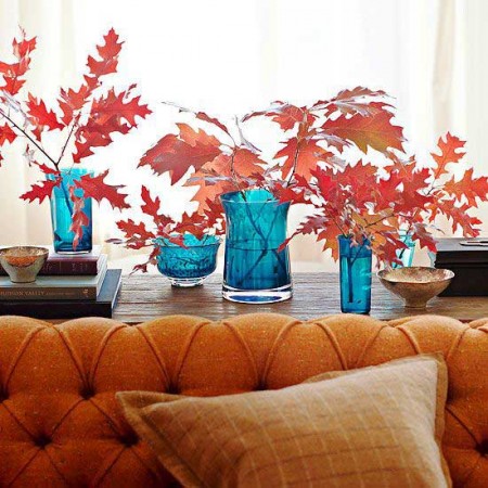A blue vase with autumn-inspired red leaves in it.