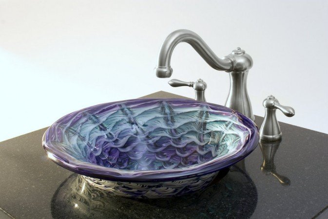 A blue and purple glass vessel sink on top of a black counter to beautify your bathroom.