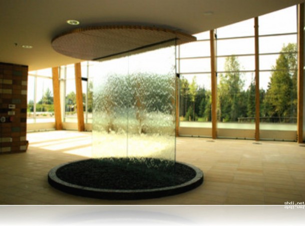 A large circular water fountain with water walls in a lobby.