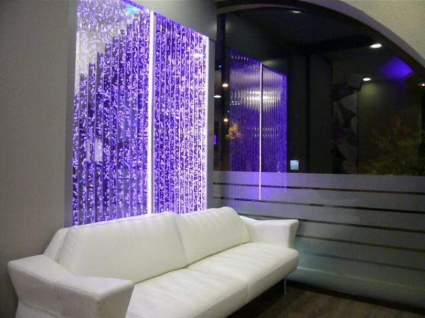 A white couch is in front of a purple wall.