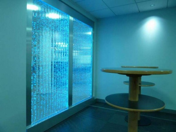 A room with a blue glass wall reminiscent of water.