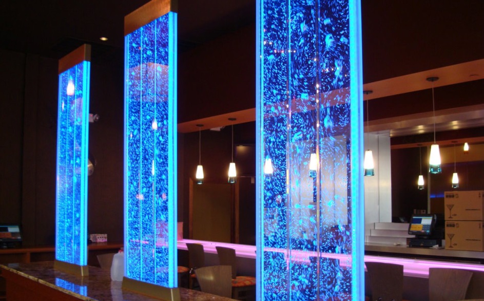 A large water wall in a restaurant with blue lights.