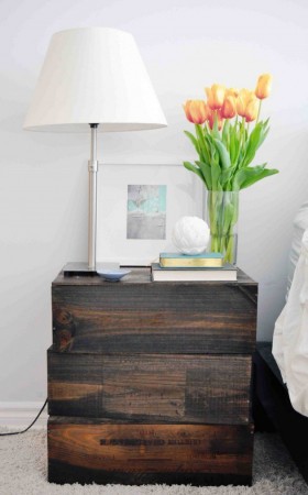 A nightstand with flowers and a lamp.