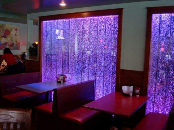 A restaurant with purple lights and water walls.