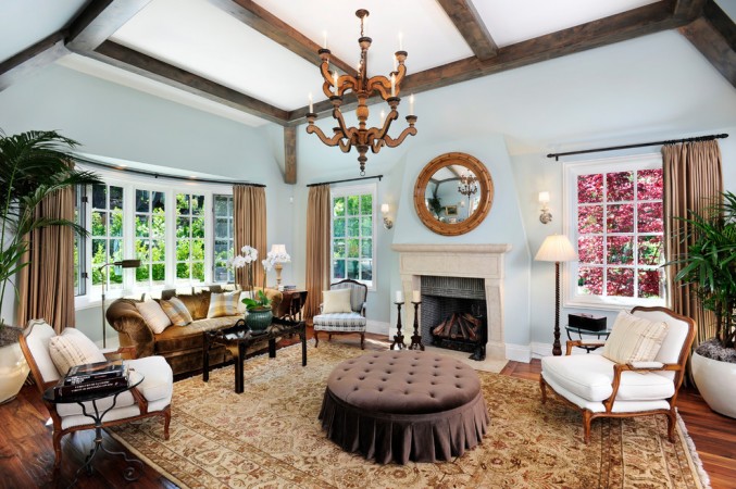 An elegant living room with a fireplace and a chandelier showcasing an earthy brown interior color scheme.