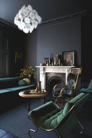 Dark charcoal walls and deep green upholstery give this room distinction