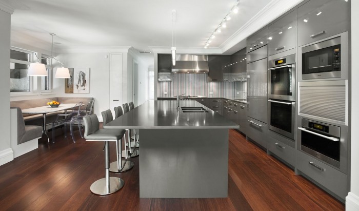 A modern kitchen with stainless steel appliances and hardwood floors designed to be open and spacious.