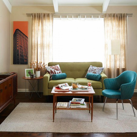 A living room with a green couch and a blue chair, showcasing Mid-Century Modern style.
