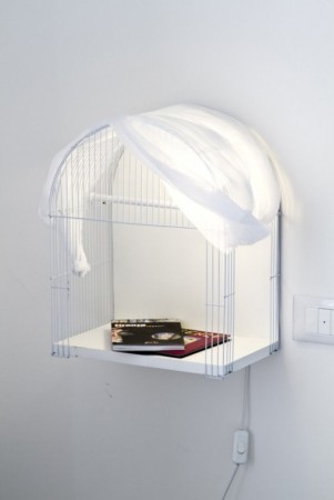A white bird cage with a cover on it.