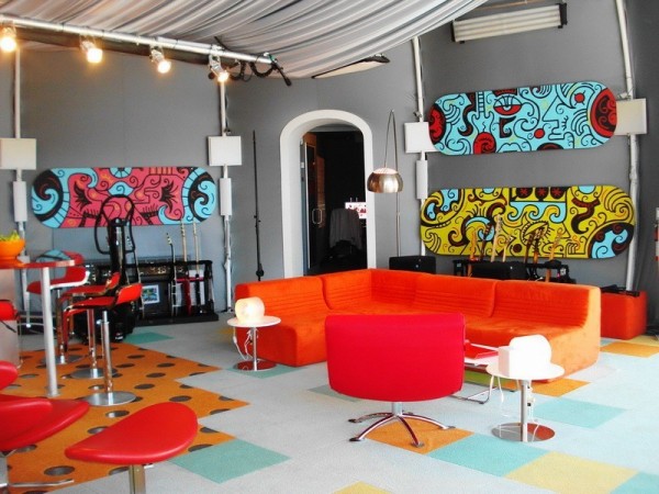 A pop art living room with orange couches and chairs.