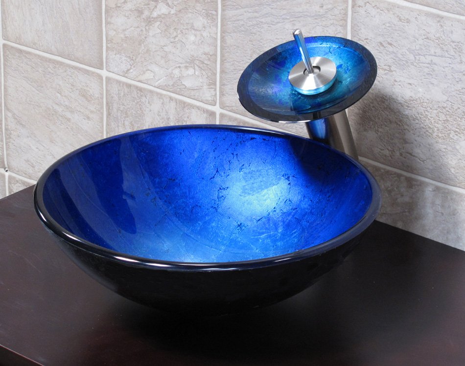 A blue glass vessel sink on top of a tiled wall from 18 Vessel Sinks to Beautify Your Bathroom.