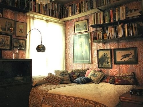 A private bedroom with many beautiful bookshelves and a cozy bed.