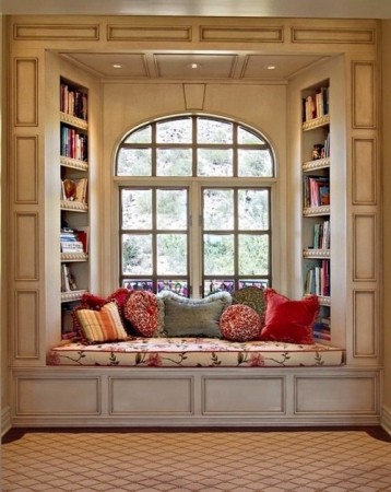 A beautiful window seat in a private room surrounded by bookshelves.