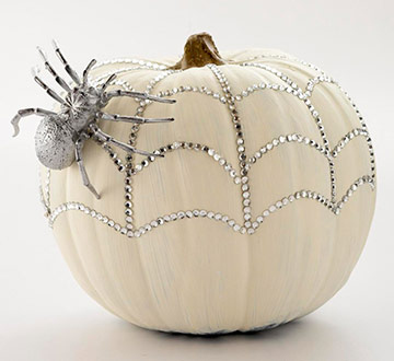 A white pumpkin adorned with a spider and rhinestones, crafted by Michaels.