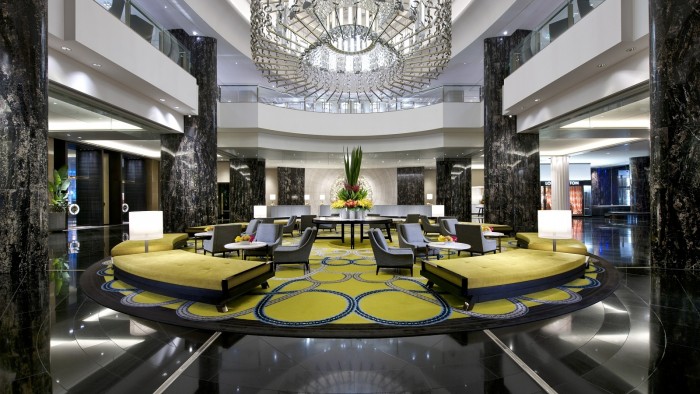 Lobby of a hotel with a large chandelier showcases interior design expertise.