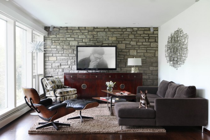 A mid-century modern living room with a tv on the wall.