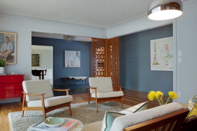A living room with blue walls and a wooden floor showcasing a Mid-Century Modern style.