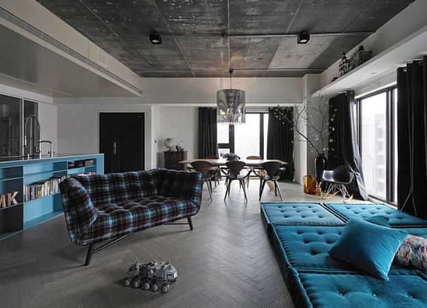 An artistically designed living room featuring blue couches and a black ceiling.