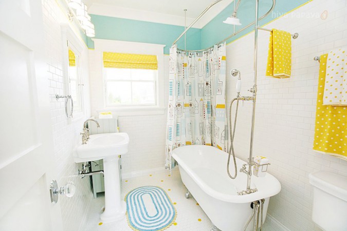 A yellow and white bathroom with a tub and sink showcasing the elegance of the clawfoot bathtub.