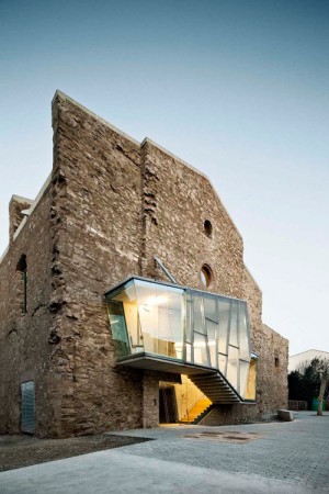 A historic church transformed into a family home, featuring a stone building with a glass facade.