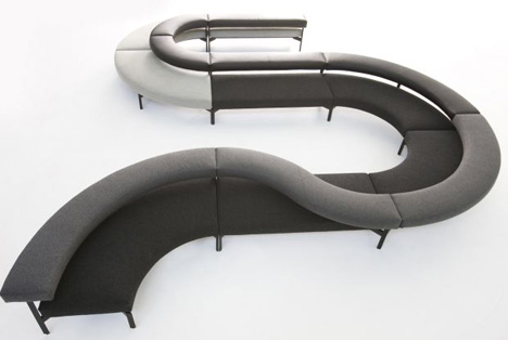 A unique set of curved couches made of gray and black fabric.