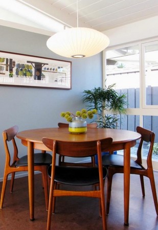 A mid-century modern dining room featuring a wooden table and chairs.