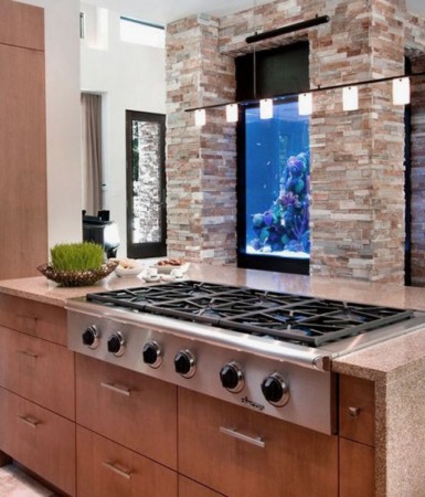 A kitchen with an aquarium in the wall.