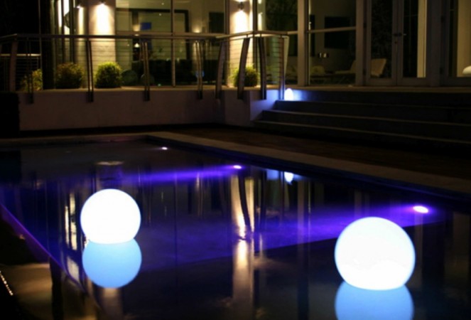 Two illuminated balls in a pool at night.